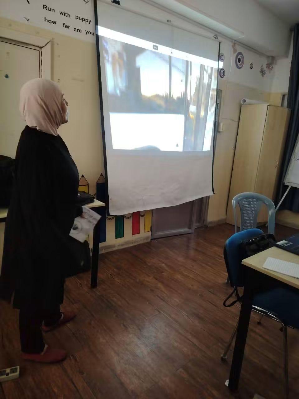 A woman watching a projected film in a community classroom